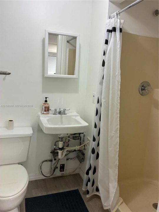 Wall-mounted sink with dual-handle chrome faucet, medicine cabinet with white frame, and enclosed shower stall with integrated chrome fixtures