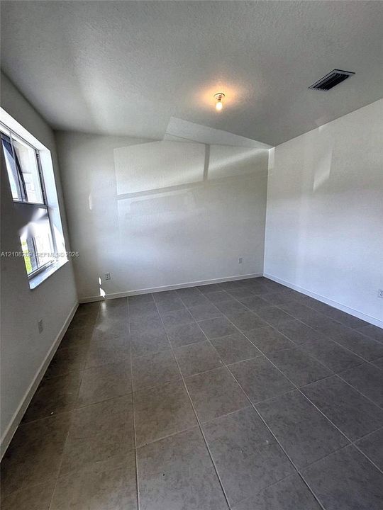 Neutral-toned tile flooring, tall windows providing natural light, and a central ceiling light fixture