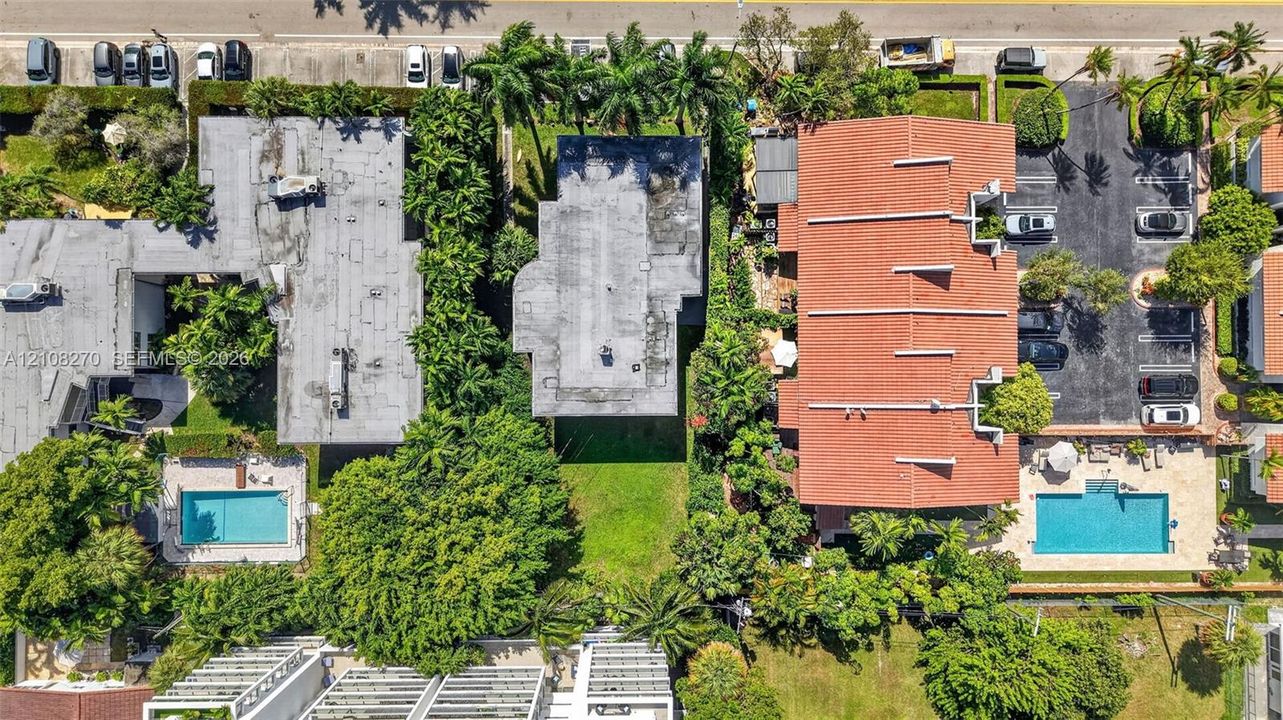 Aerial perspective showcasing a parcel of land with established green space, mature canopy trees, lush landscaping, and integrated paved parking