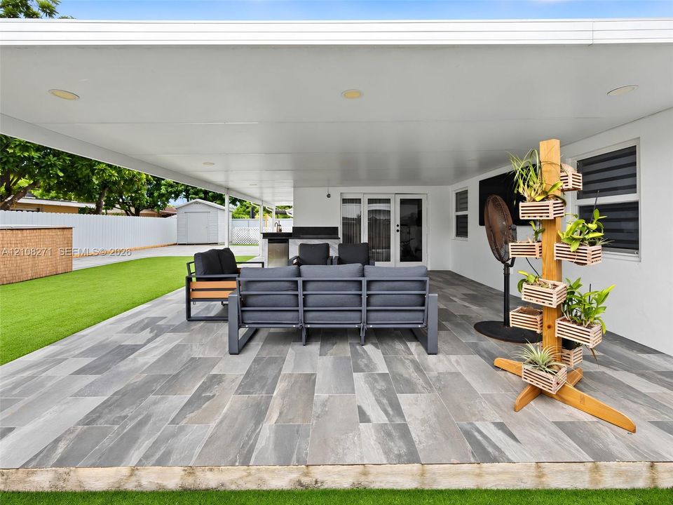 Covered patio featuring large-format stone-finish tile flooring, recessed lighting, and a built-in outdoor kitchen counter