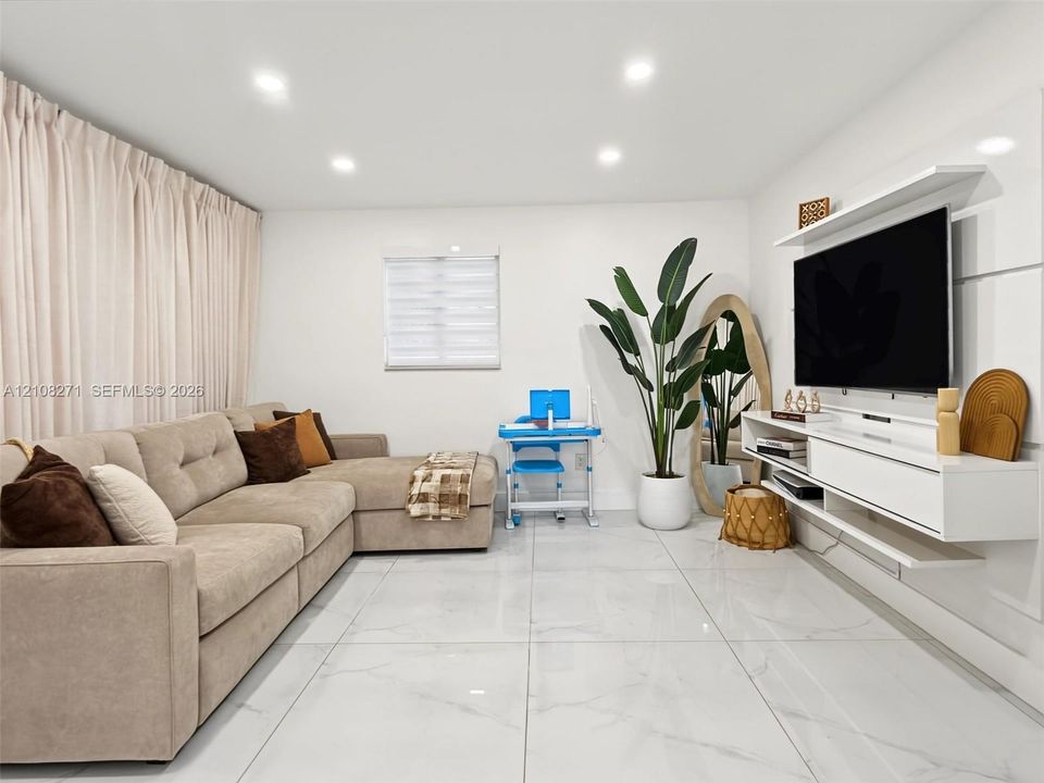 Living space featuring large-format tile flooring, recessed lighting, and a custom white wall-mounted media console