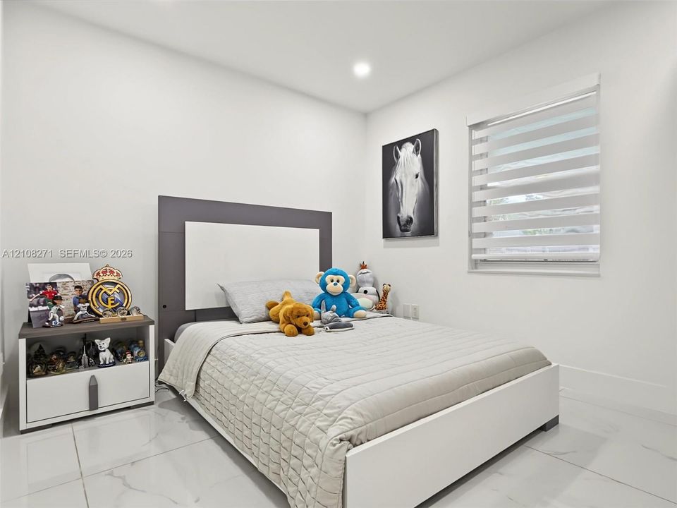 Neutral-toned interior featuring large-format tile flooring, recessed ceiling lighting, and a dual-shade roller window treatment