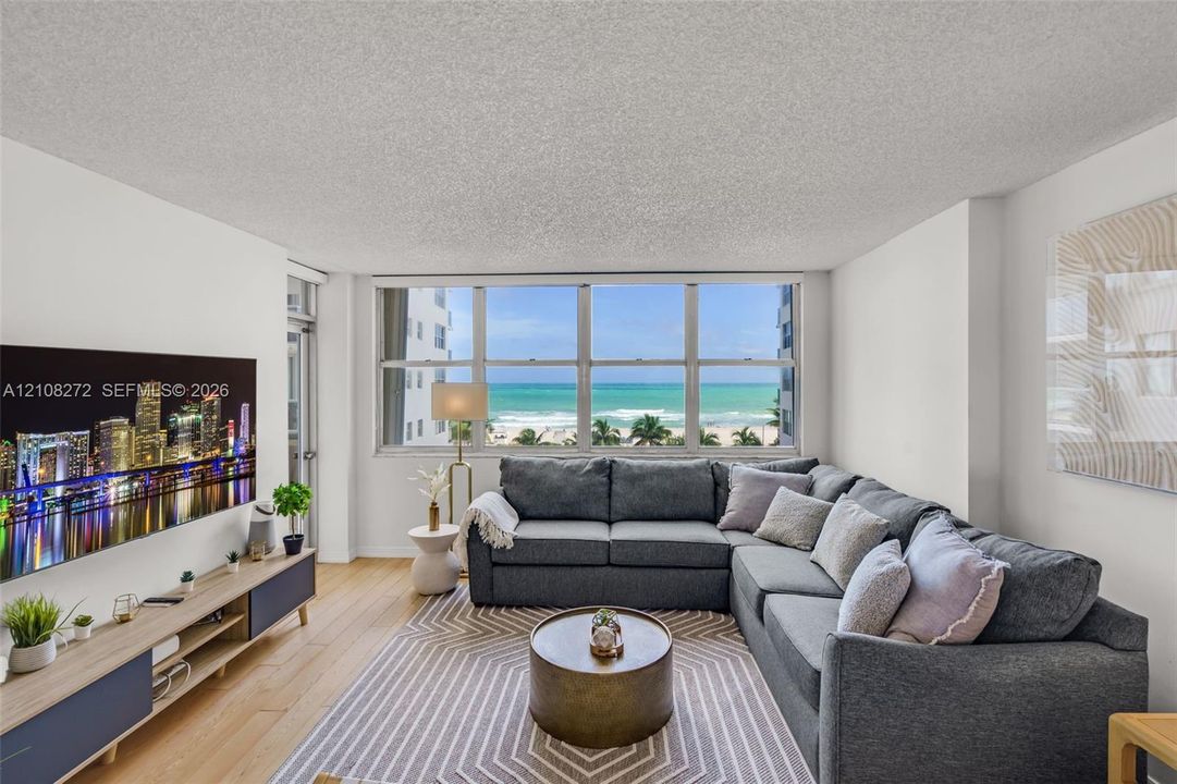 Expansive multi-pane window featuring coastal scenery, wood-finish flooring, and neutral wall tones