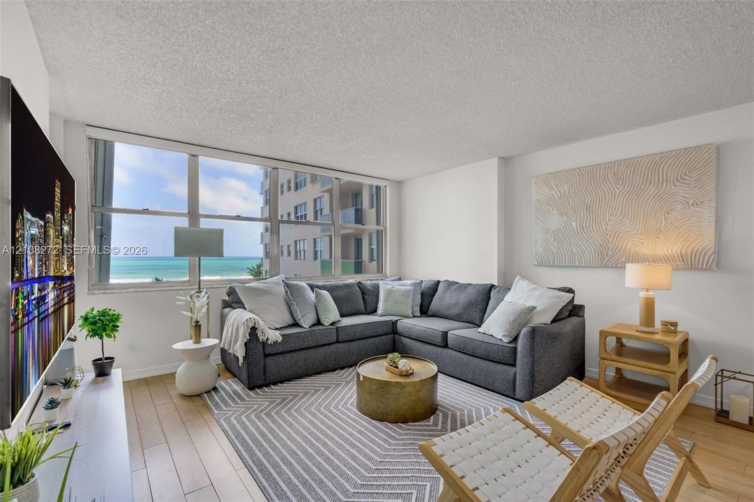 Living area featuring floor-to-ceiling windows, wood-finish flooring, and ocean exposure