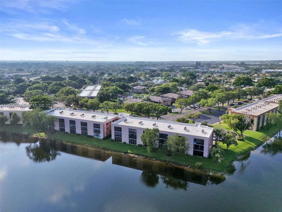 Waterfront multi-story residential building featuring exterior balconies, flat roofline, and landscaped perimeter grounds