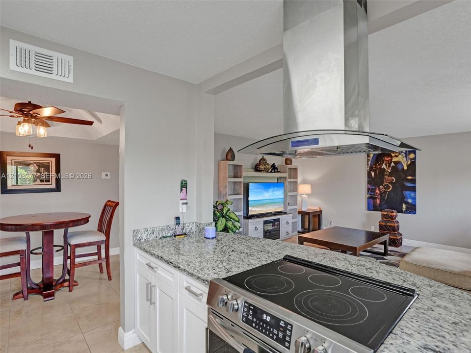 Kitchen featuring a stone countertop peninsula, stainless steel slide-in electric range, and a ceiling-mounted stainless steel chimney-style range hood