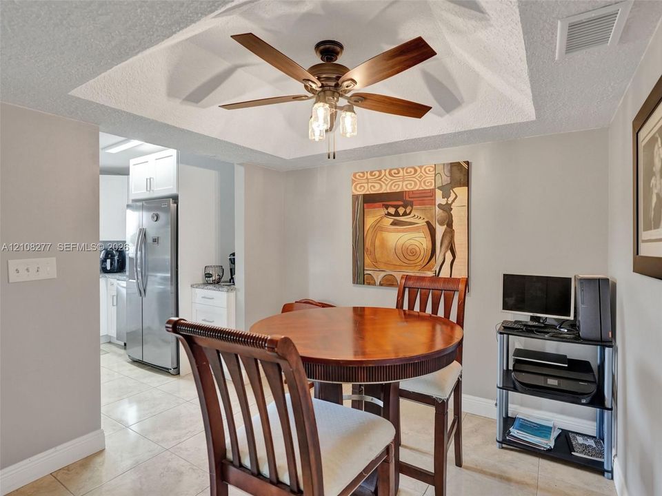 Tray ceiling with a central multi-blade ceiling fan and integrated light fixture, featuring tile flooring throughout