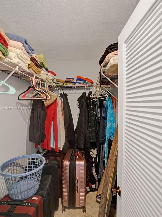 Storage space featuring ventilated wire shelving, neutral wall tones, and a louvered entry door with metallic hardware