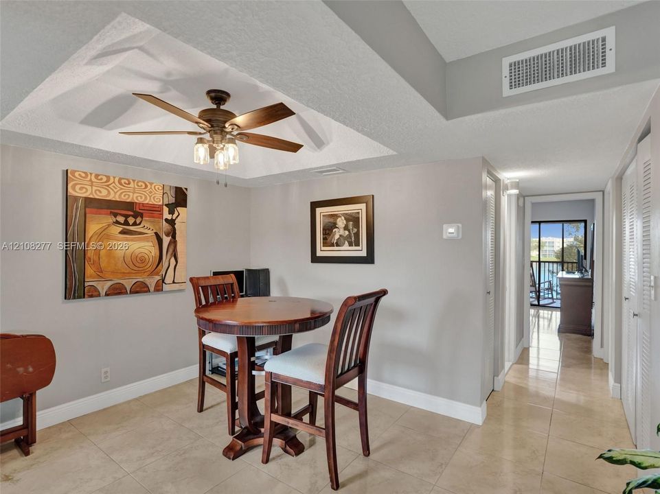 Tray ceiling featuring a central five-blade ceiling fan with integrated light fixture, neutral wall finishes, and large-format tile flooring