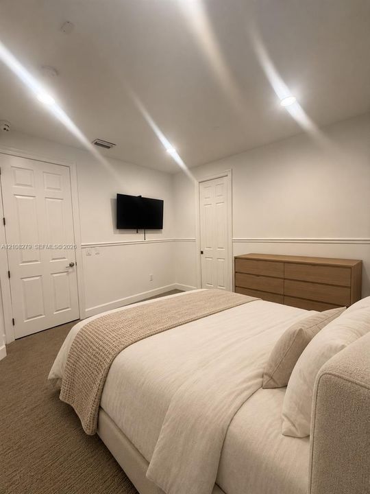 Neutral-toned carpeted flooring, wall-mounted television, recessed lighting, chair rail molding, and two-panel interior doors