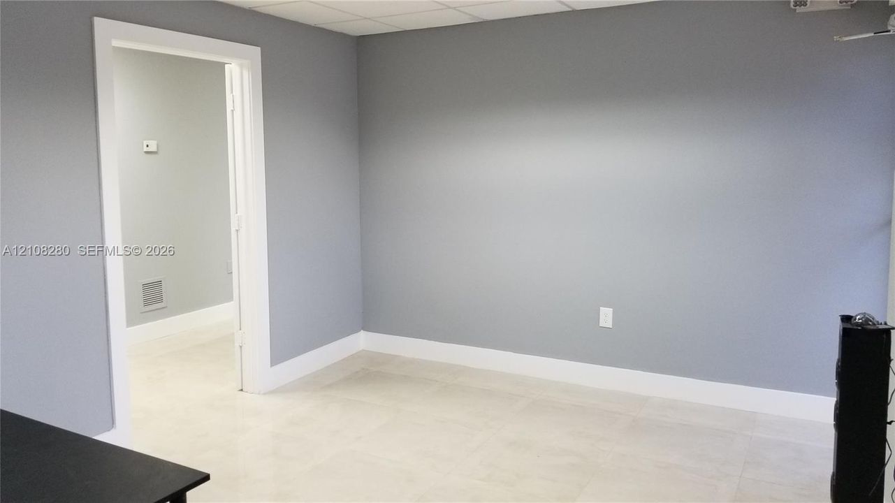 Interior room featuring neutral wall paint, tile flooring, and a drop ceiling