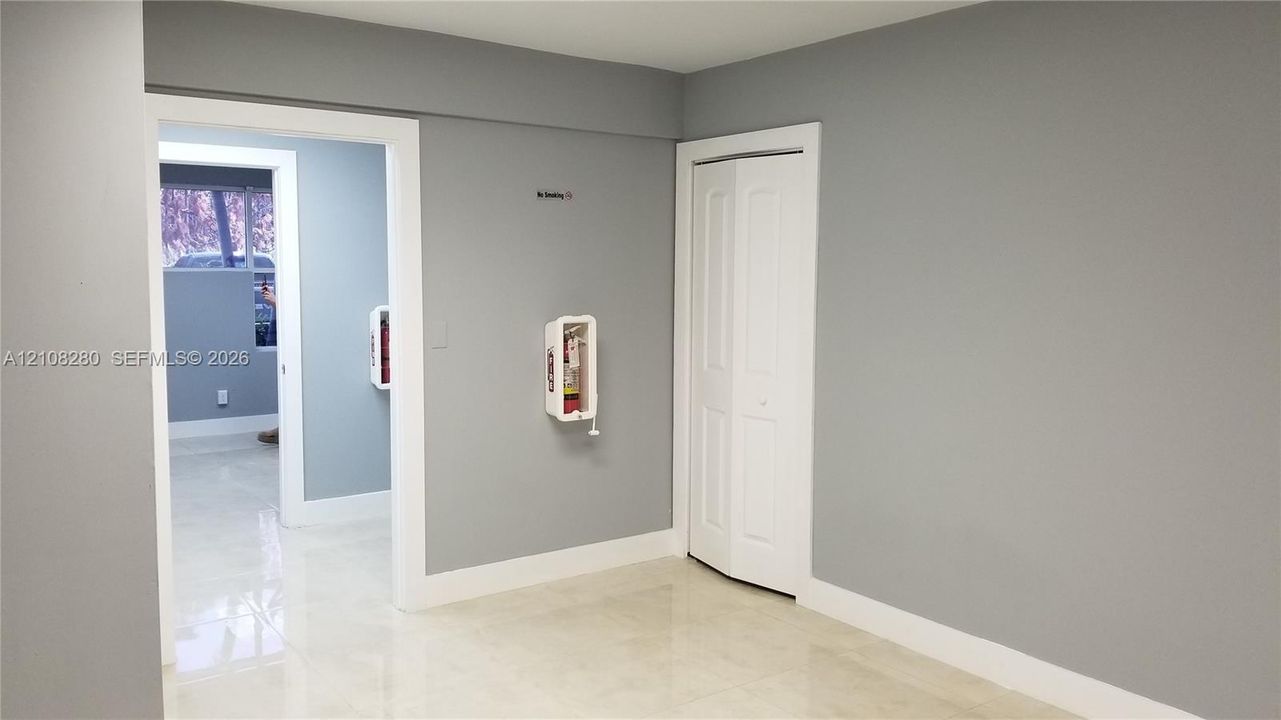 Polished tile flooring, neutral grey wall paint, white trim, and a bi-fold closet door