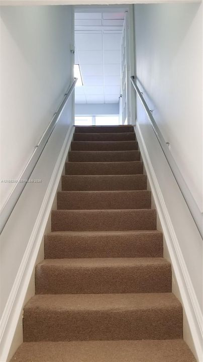 Staircase featuring wall-to-wall carpeting and dual metal handrails
