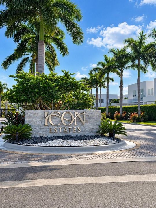 Stone-clad monument signage featuring metal lettering, surrounded by professional landscaping, palm trees, and a paved circular driveway