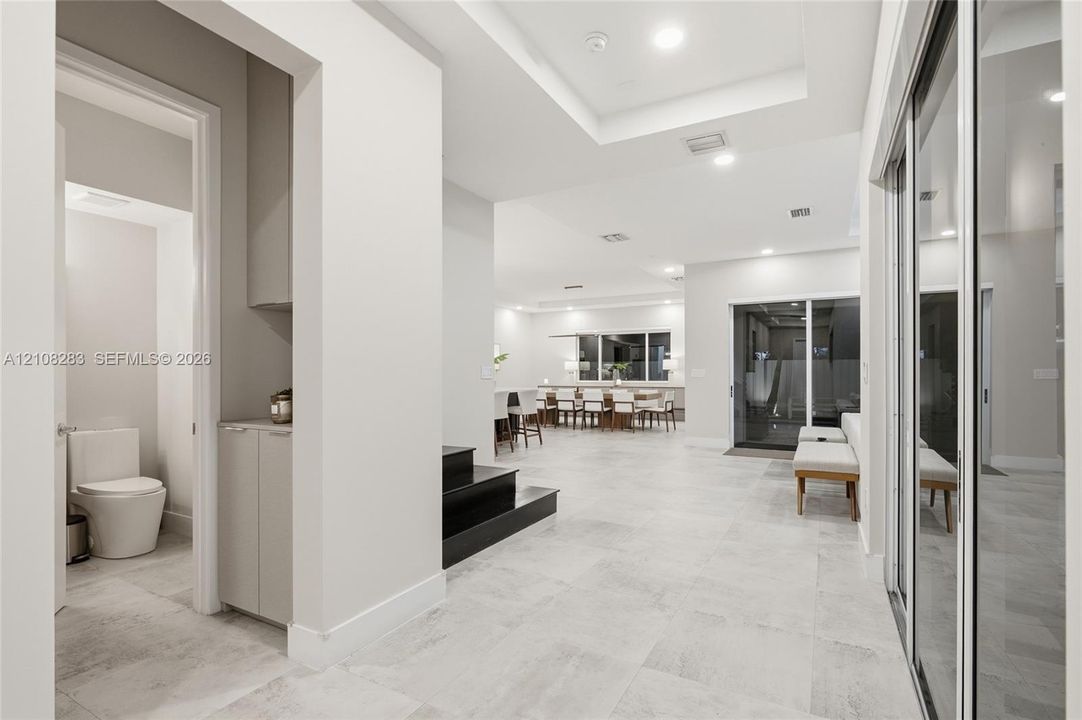 Interior space featuring large-format tile flooring, recessed ceiling lighting, tray ceilings, built-in cabinetry, and sliding glass doors