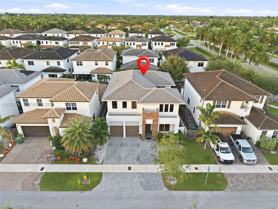 Two-story residence featuring a tile roof, paved driveway, multi-car garage, and a vertical wood-plank architectural accent