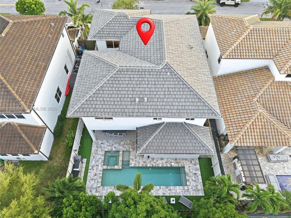Two-story residence featuring a tile roof, an integrated in-ground pool with a spa, and a stone-paver patio
