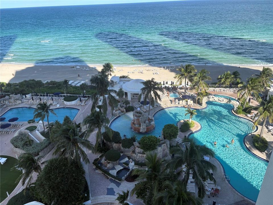 Oceanfront property featuring multiple resort-style swimming pools, rock-feature waterfalls, landscaped tropical grounds, and direct beach access