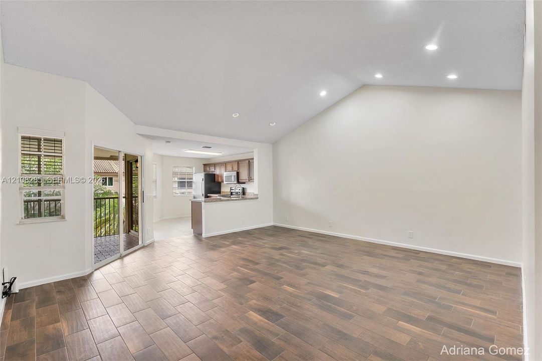 Vaulted ceilings with recessed lighting, wood-finish tile flooring, and sliding glass doors