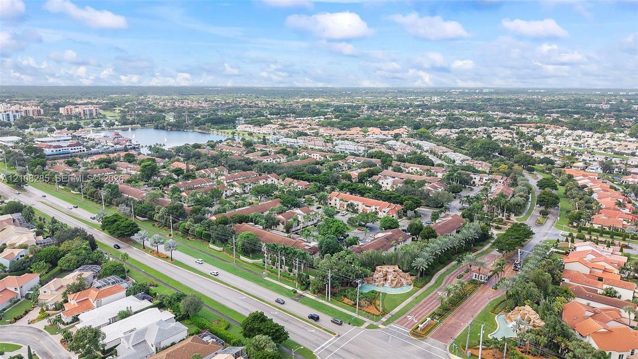 Aerial perspective of a multi-residential community featuring tile roofing, mature landscaping, paved roadways, and decorative rock water features