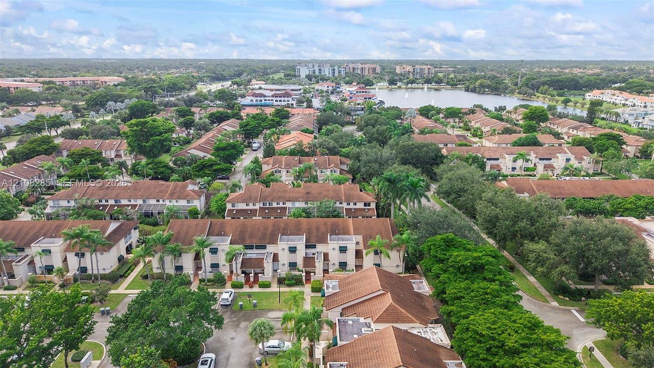 Aerial perspective of multi-family residences featuring tile roofing, stucco exteriors, mature landscaping, and tree-lined grounds