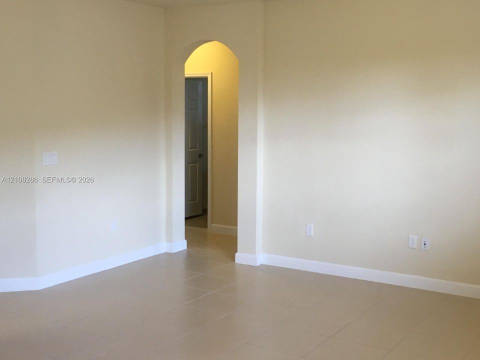 Neutral walls with arched doorway featuring classic architectural detailing and neutral-toned tile flooring
