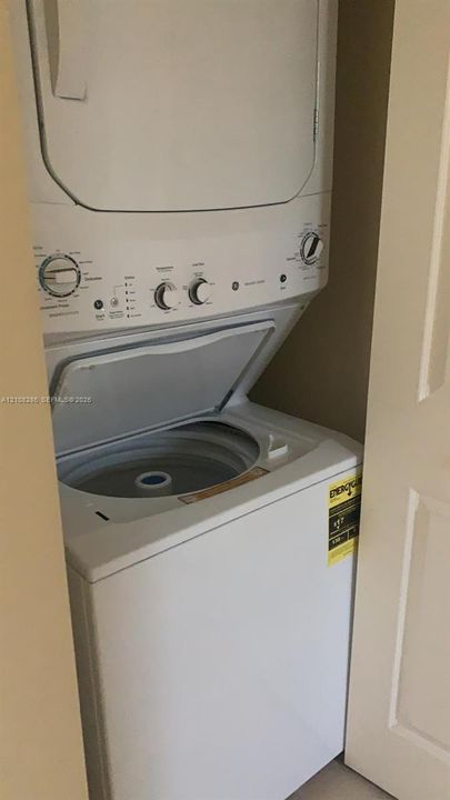 Stacked white laundry unit featuring a top-loading washer and integrated control dials