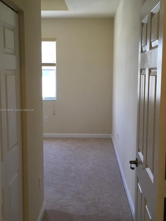 Neutral-toned room featuring neutral carpeting, a single-panel window with a blind, and six-panel interior doors