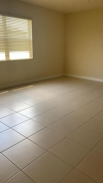 Neutral-toned ceramic tile flooring, horizontal window blinds, and solid-colored walls