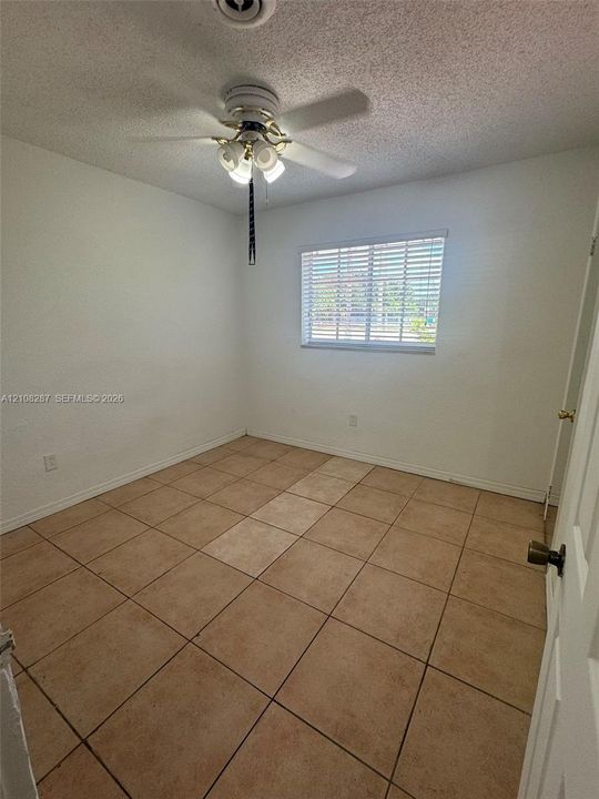 Neutral-toned tile flooring, ceiling fan with integrated multi-bulb light fixture, and horizontal window blinds