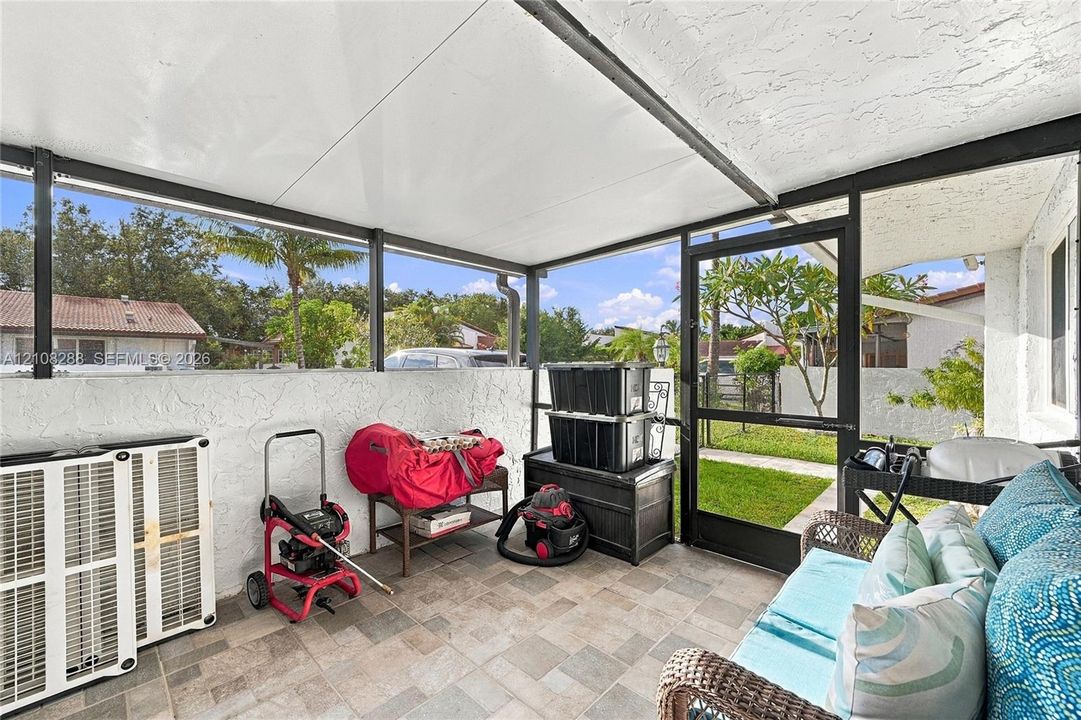 Screened-in patio with tile flooring, textured stucco walls, and a metal-framed roof structure
