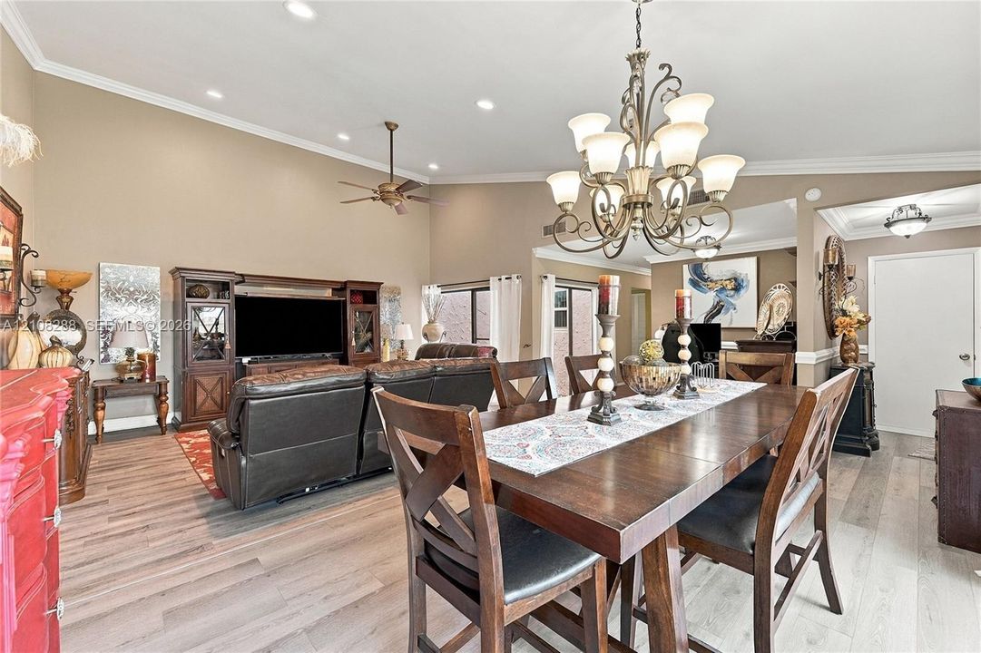 Vaulted ceilings with recessed lighting, wood-finish flooring, and an ornate multi-arm chandelier