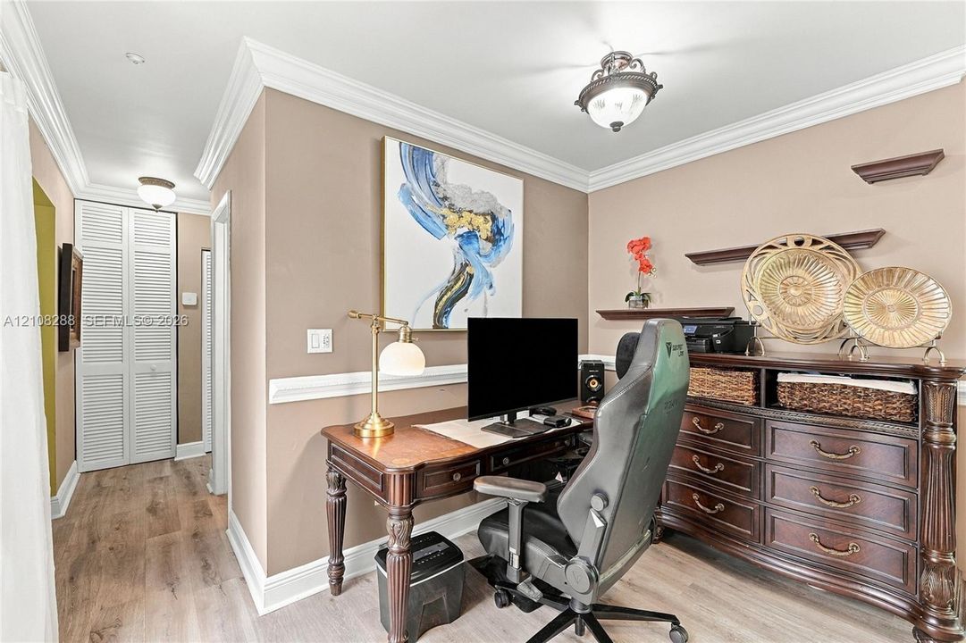 Room featuring wood-finish flooring, crown molding, chair rail trim, louvered bi-fold closet doors, and a semi-flush mount ceiling fixture