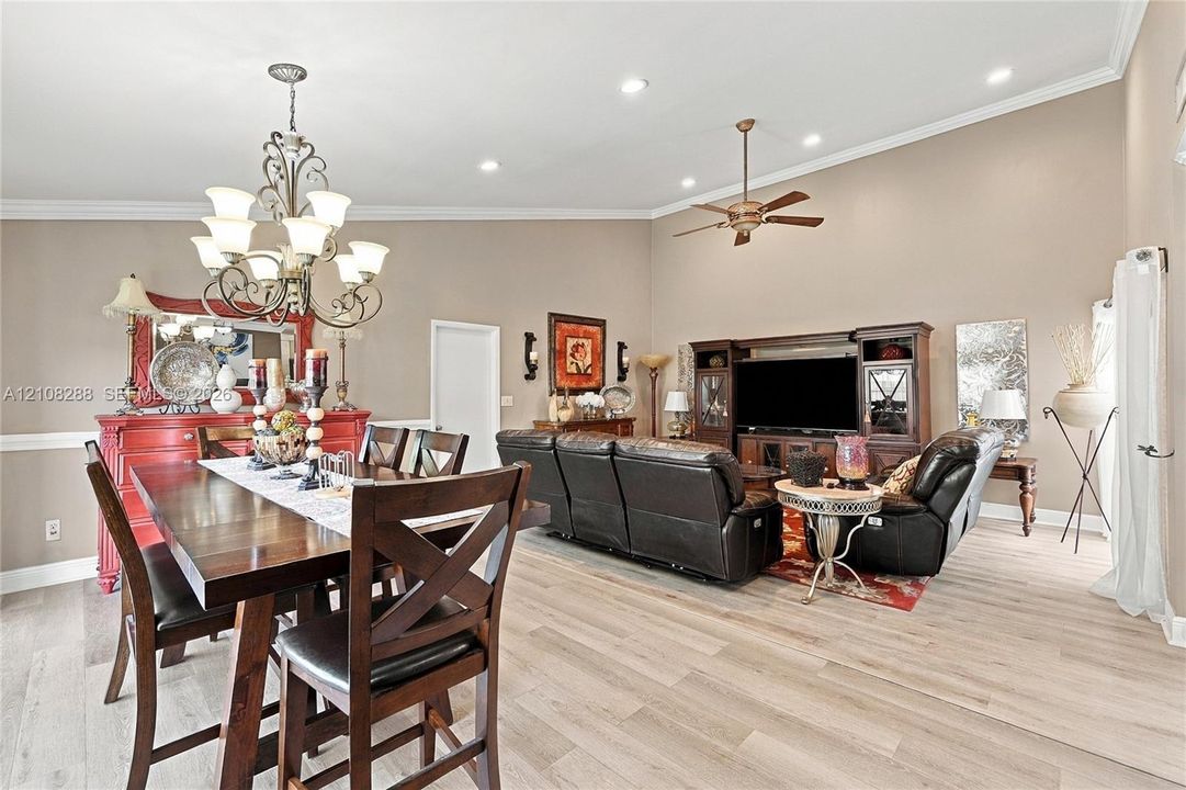 Vaulted ceilings with recessed lighting, wood-finish flooring, crown molding, and an ornate wrought-iron chandelier