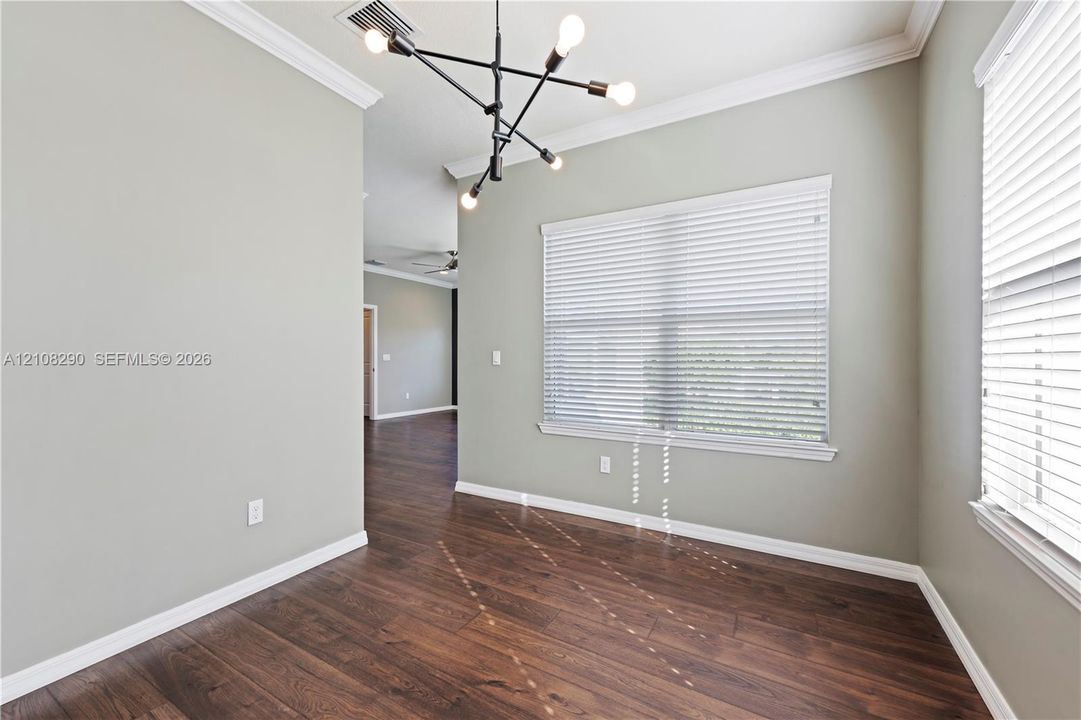 Interior space featuring wood-finish flooring, crown molding, a modern multi-arm sputnik chandelier, and horizontal window blinds