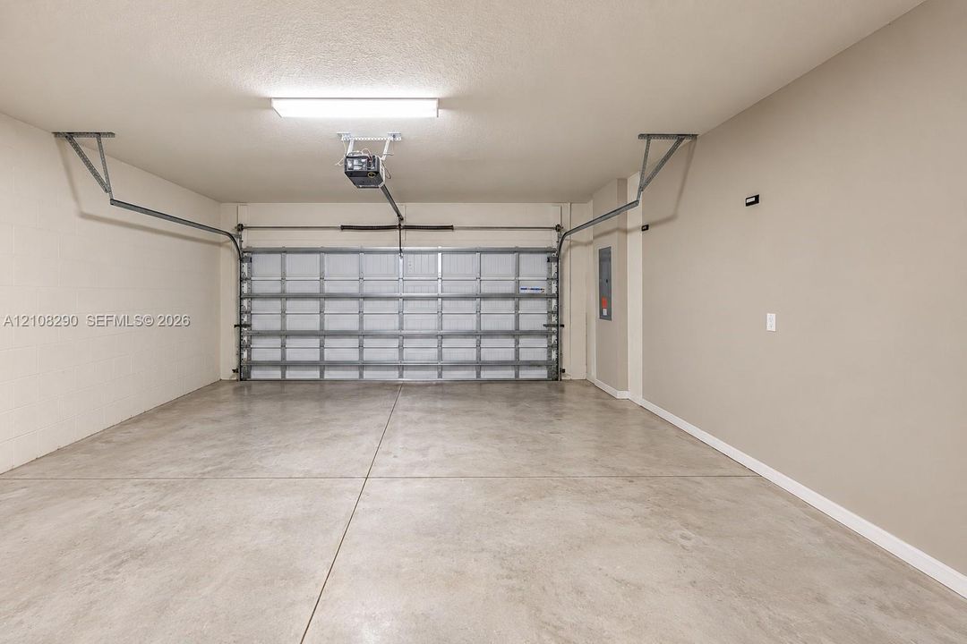 Two-car garage featuring a concrete floor, finished walls, overhead lighting, and an automated door opener