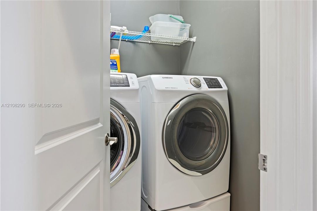 Laundry area featuring a side-by-side washer and dryer set with pedestal bases and a mounted wire shelving unit