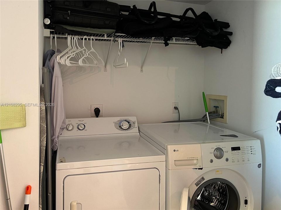 Dedicated laundry area featuring a white front-load washer and a top-load dryer, complemented by a white wire overhead shelving system