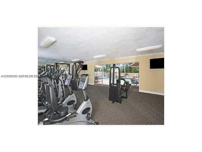 Fitness center featuring wall-to-wall carpeting, flush-mount lighting, and floor-to-ceiling glass sliding doors