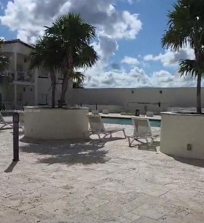 Swimming pool area featuring stone pavers, tiered landscaping with built-in planters, and palm trees