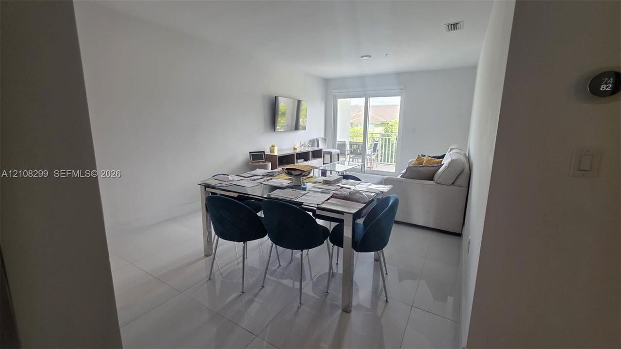 Open-concept interior featuring large-format tile flooring, neutral wall tones, and glass sliding doors providing exterior access