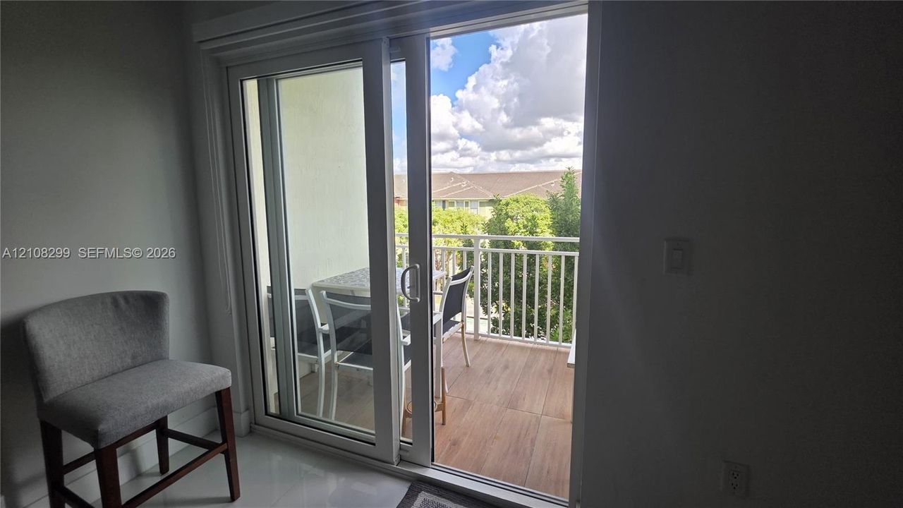 Sliding glass door opening to a private balcony featuring white metal railings and wood-finish flooring