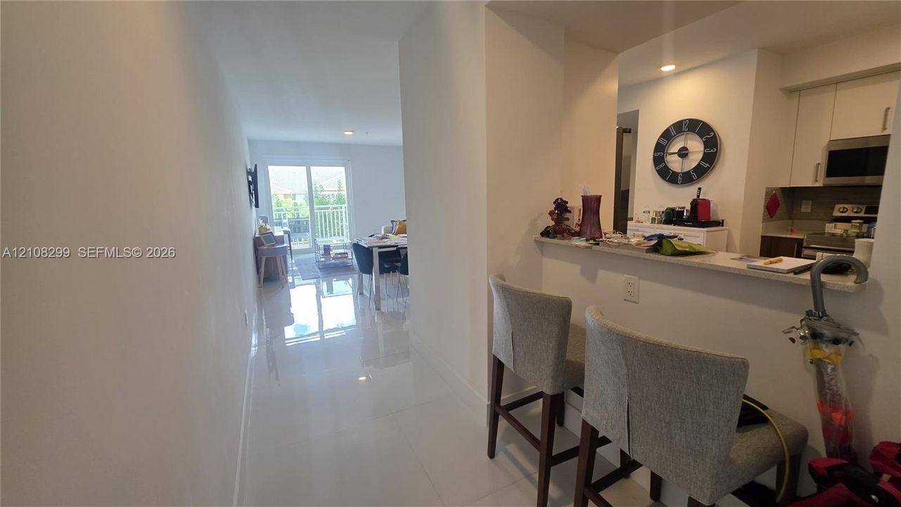 Kitchen featuring a pass-through breakfast bar with a solid surface countertop, white cabinetry, integrated microwave, and polished tile flooring