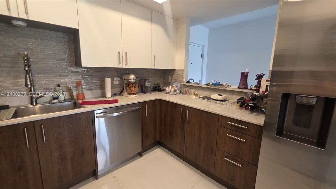 Kitchen featuring two-tone cabinetry, stone-surface countertops, horizontal tile backsplash, stainless steel appliances, and a gooseneck faucet