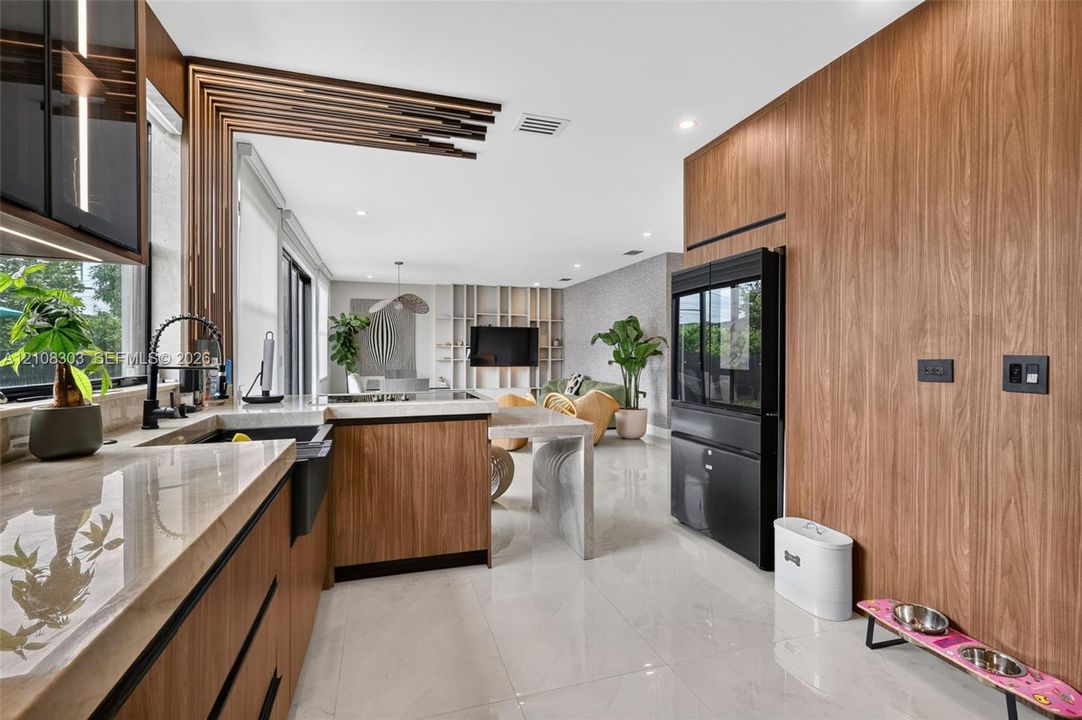 Kitchen featuring wood-finish cabinetry, stone countertops, a deep basin sink with a matte black faucet, integrated full-height cabinetry, and architectural wood-slat ceiling detailing