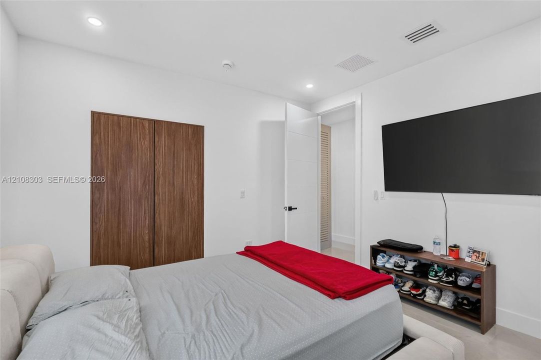 Wood-finish closet doors, recessed lighting, and solid-core interior doors with matte black hardware