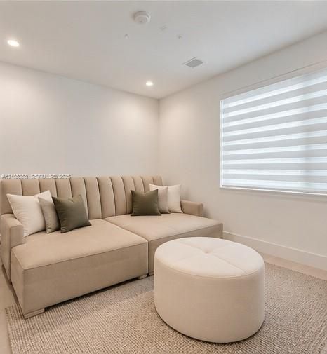 Neutral-toned room featuring recessed ceiling lighting and adjustable window blinds