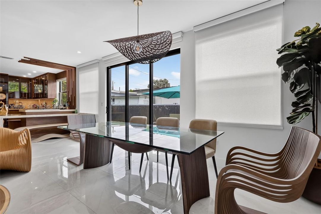 Large-format tile flooring, oversized black-framed sliding glass doors, and a custom architectural pendant light fixture