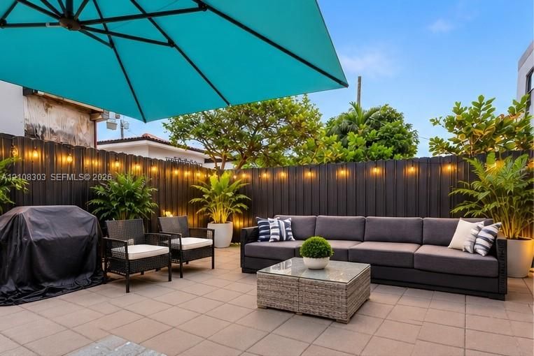 Enclosed patio featuring paved flooring, horizontal metal perimeter fencing, and integrated string lighting