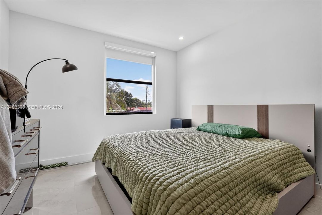 Neutral interior featuring smooth white walls, recessed ceiling lighting, light-toned flooring, and a single-pane window
